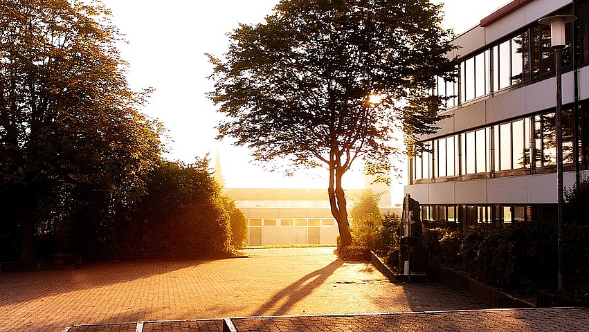 Schulgebäude und Schulhof beim Sonnenaufgang